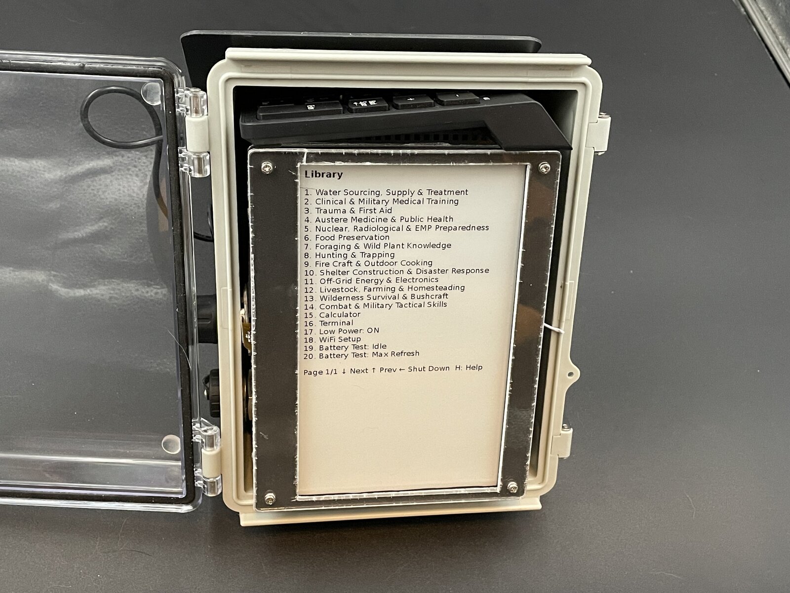The SPRG 2.0 waterproof case open, showing the detachable keypad tucked inside and the e-ink screen mounted on its rigid frame